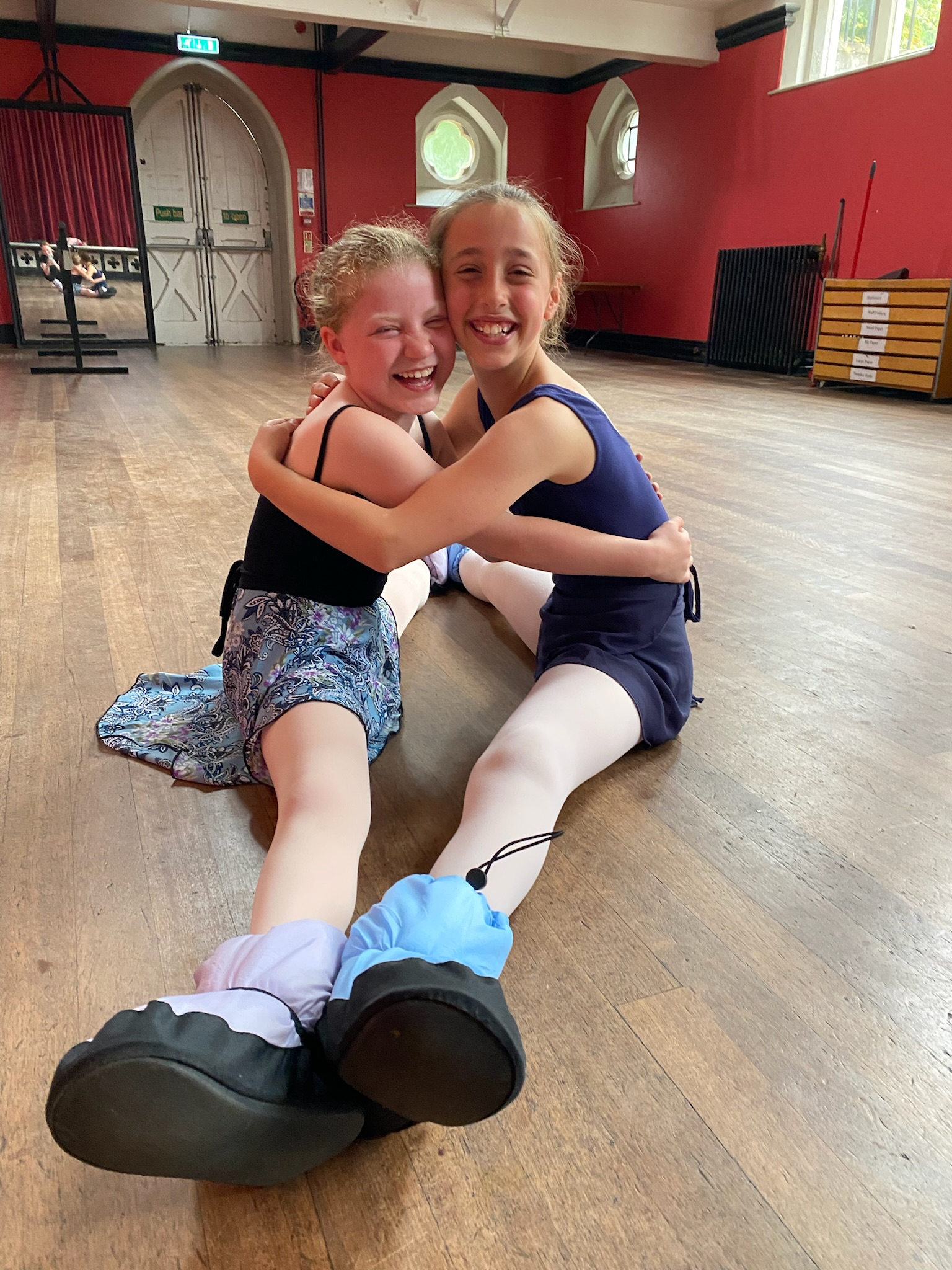 Two young dancers sharing a hug in a Wimbledon Village hall